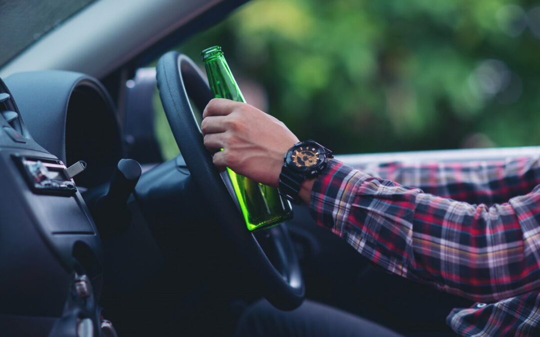 man holding beer bottle while driving car