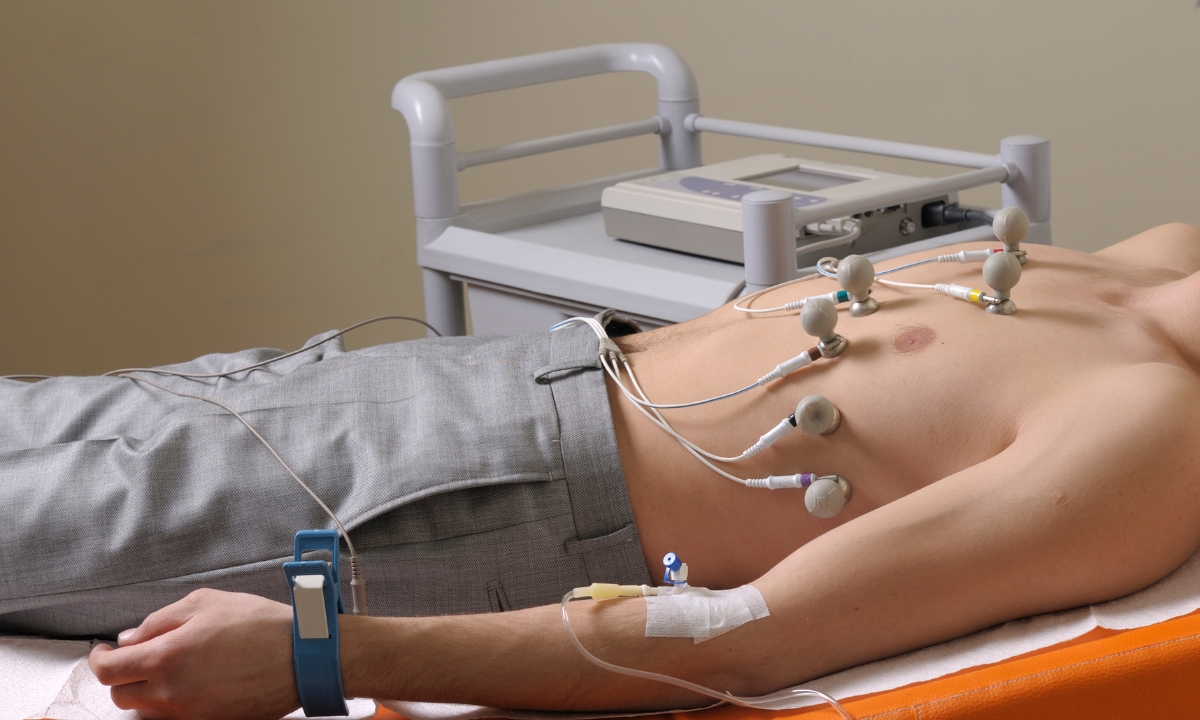a shirtless man in a hospital bed with sensors on his torso