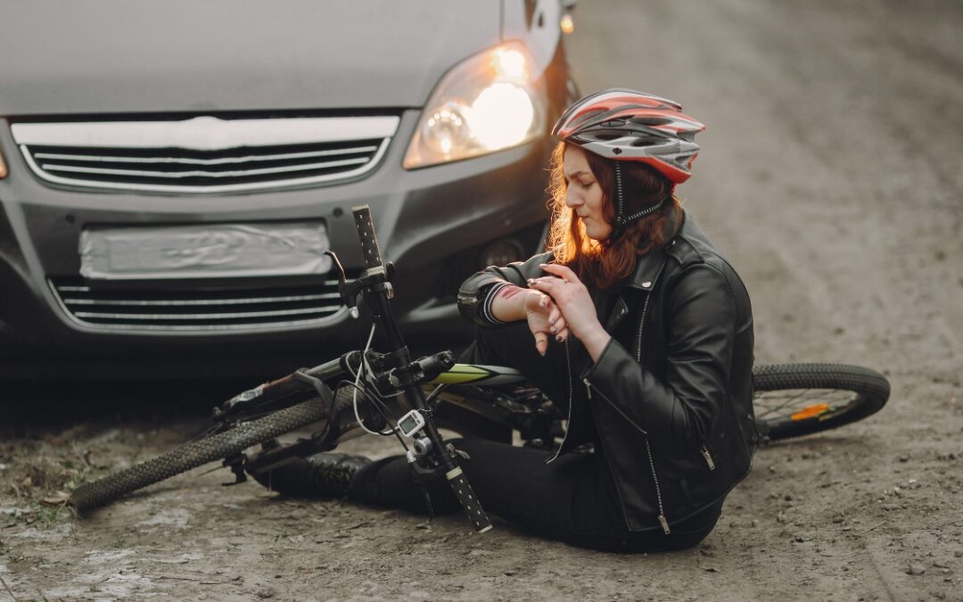 woman sitting in front of a car with her bike after being hit by the car